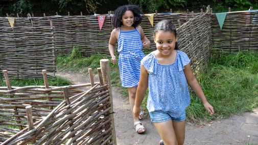 Two girls in blue outfits running through a maze